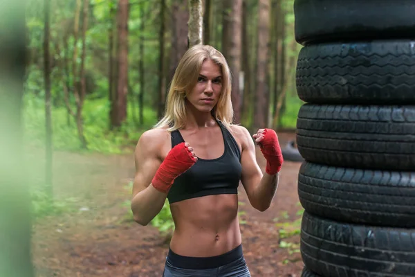 Woman boxer professional fighter posing in boxing stance, working out outdoors