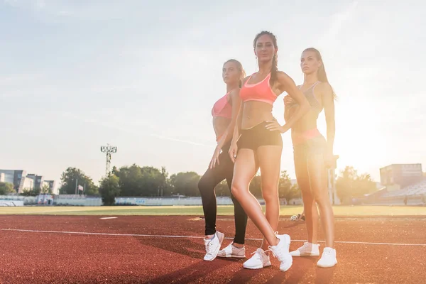 Grupo de jovens esportistas aptos em pé no estádio de atletismo e posando . — Fotografia de Stock