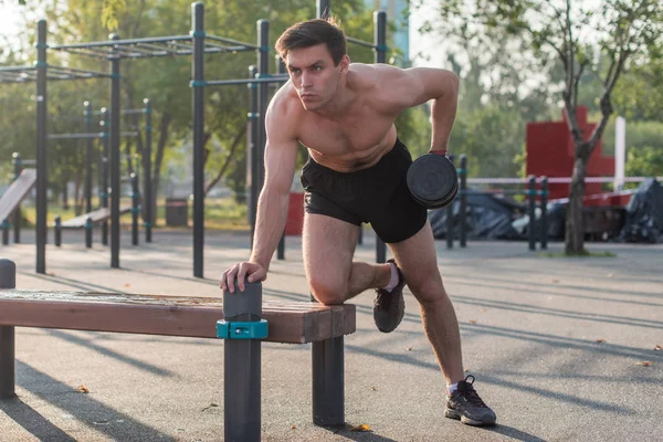 Muscular man lifts the dumbbell. Back exercise. Single arm dumbbell row.