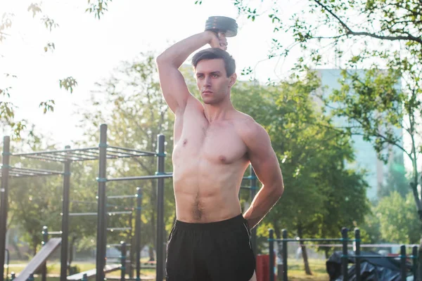 Atleta masculino muscular com braços levantados fazendo exercícios de elevação halteres . — Fotografia de Stock