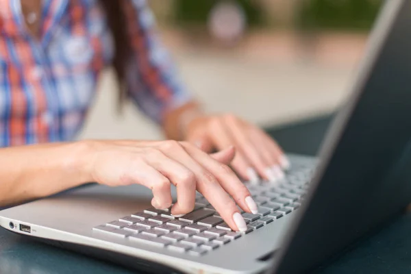 Ung kvinna att skriva på en laptop tangentbord arbetar utomhus — Stockfoto