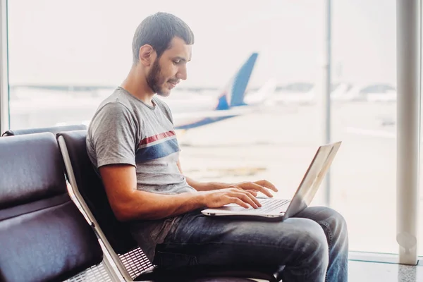 Молодий чоловік використовує ноутбук в терміналі аеропорту — стокове фото