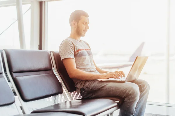 Junger Mann benutzt Laptop im Flughafen-Terminal — Stockfoto