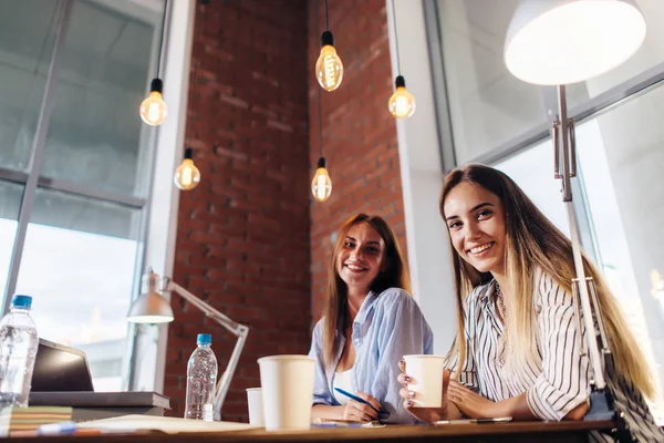 Three smiling female college students working on project together in classroom — Stock Photo, Image