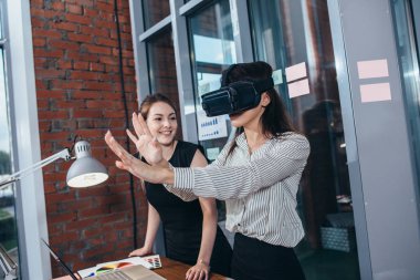 İki kız öğrenci sınıfta bir dersten sonra molası Vr gözlüklü 3d bir oyun oynuyor