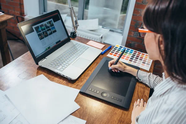 Imagen de primer plano de las mujeres dibujando un proyecto utilizando una tableta gráfica y un portátil sentado en la oficina moderna — Foto de Stock