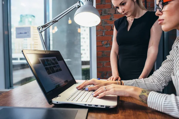 Vrouwelijke binnenhuisarchitect, werken met een klant die kijken naar foto's met behulp van laptop zit op moderne studio — Stockfoto