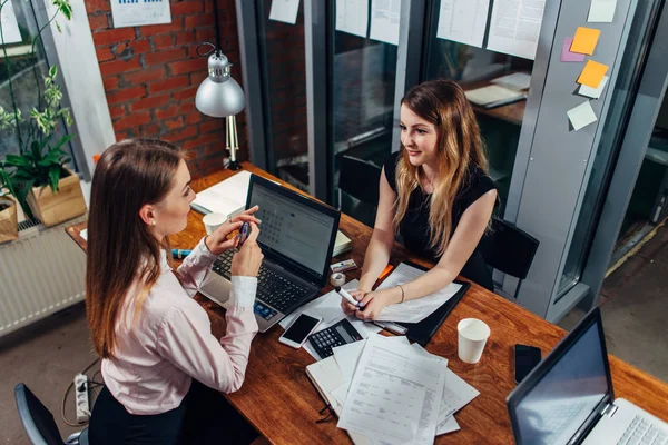 Kvinnliga studenter som arbetar på skola uppdrag använder bärbara datorer sitter vid skrivbord i ett grupprum — Stockfoto