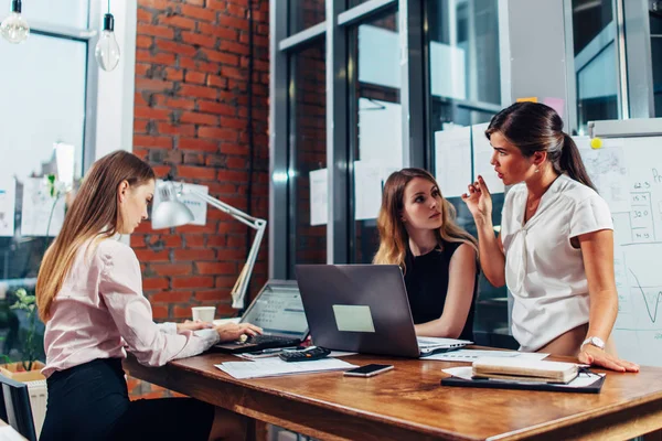 Dizüstü bilgisayarlar ve belgeleri sorunları ve bir boardroom planında görüşmek üzere toplanan masada oturan kadın Yöneticiler grubu