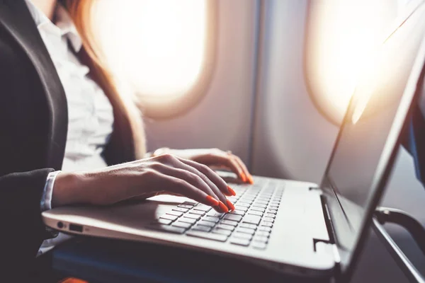 Primer plano de las manos femeninas utilizando el ordenador portátil. Mujer trabajando durante su viaje de negocios en avión — Foto de Stock