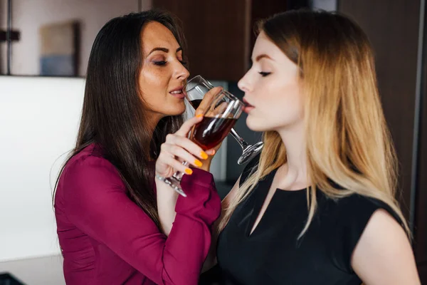 Dos novias en ropa elegante relajarse después de ir de compras, beber vino, reír y chismorrear en la cocina —  Fotos de Stock