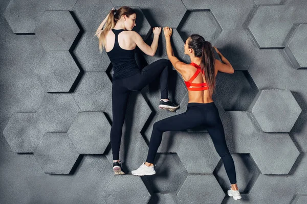 Ajustar a las mujeres posando como un escalador colgado en la pared decorativa —  Fotos de Stock