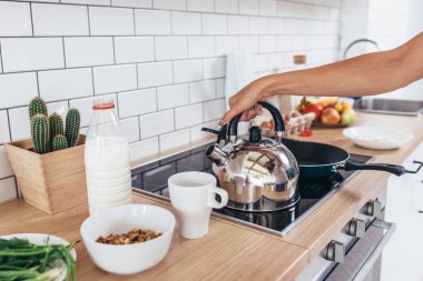 Kadın kahve yapmak için bir çaydanlık su Isıtma.