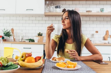 Bir fincan kahve evde mutfak arka plan karşı olan güzel kadın