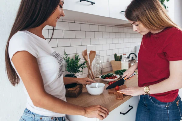 Zwei Freundinnen bereiten das Abendessen in der Küche zu und kochen Salat. — Stockfoto