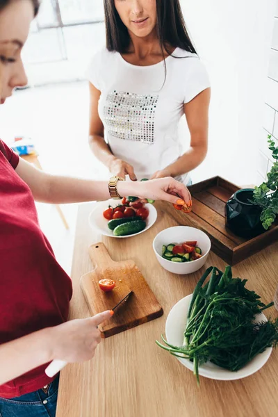 Vrouw snijden tomaat op het houten bord — Stockfoto