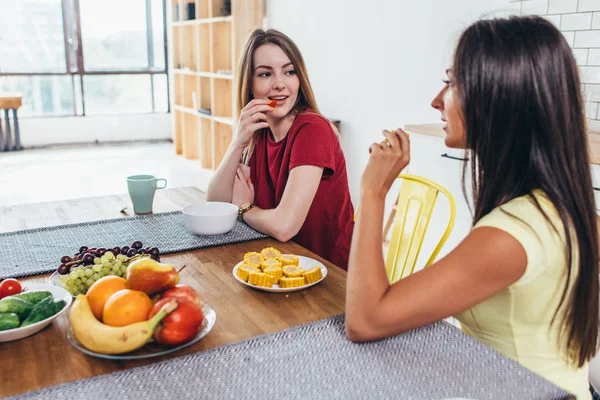 Vrienden van de vrouwen met fruit bij het ontbijt in de keuken. — Stockfoto