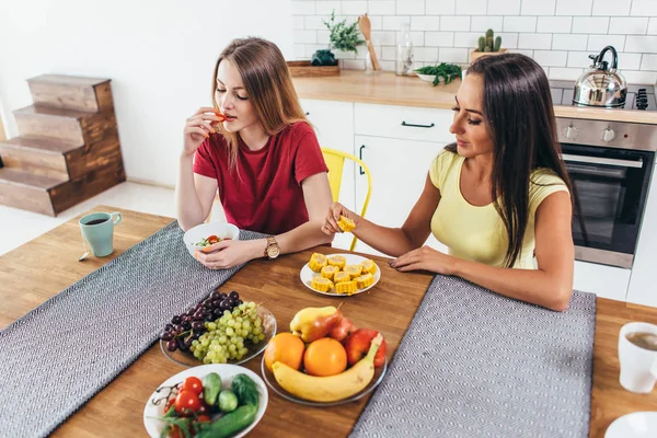 Two young women friends sitting at table talking and eating. — Stock Photo, Image