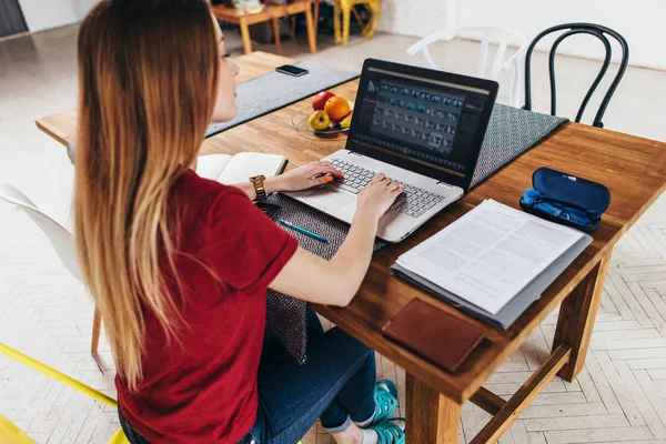 Otthon az asztalnál, a konyhában, szabadúszóként dolgozik-ra jegyzetfüzet laptop dolgozó nő. — Stock Fotó