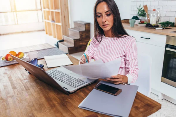 집 부엌에서 서류와 노트북을 가지고 일하는 여자 — 스톡 사진