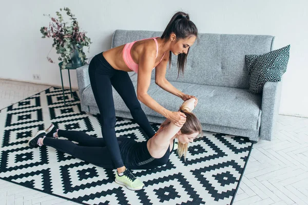 Fit mulher ajudando amigo na parte de trás alongamento treino em casa — Fotografia de Stock