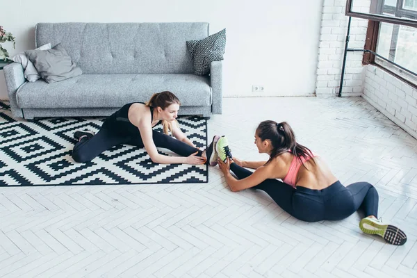 Fitte Frauen beim Stretching während sie zu Hause auf dem Boden sitzen — Stockfoto