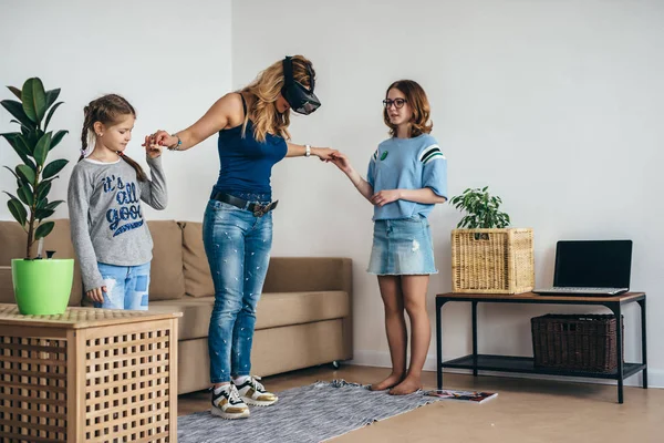 Όρθια η γυναίκα στο σπίτι χρησιμοποιώντας το ακουστικό Vr γυαλιά εικονικής πραγματικότητας στο σαλόνι με τα παιδιά. — Φωτογραφία Αρχείου
