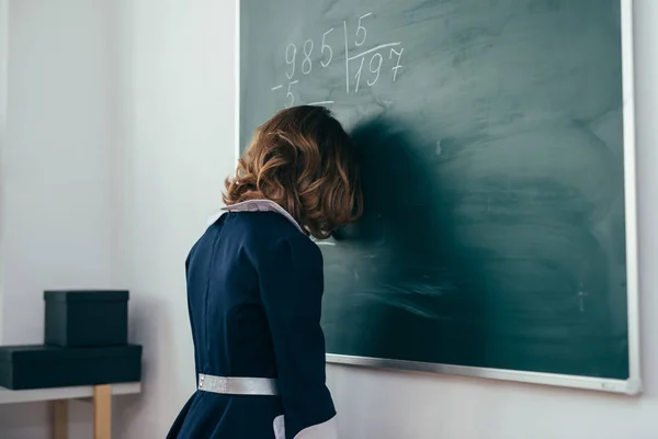 Školačka stojí s její čelo na tabuli — Stock fotografie