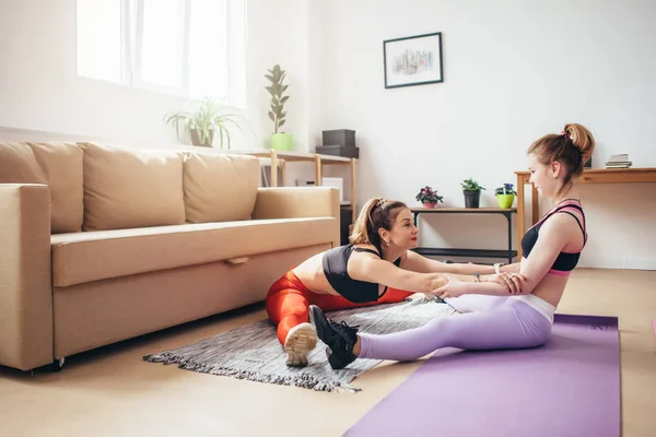 Passar kvinnor utövar och stretching hemma. — Stockfoto