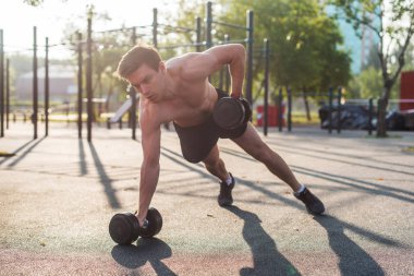 Kaslı adam halter kaldırıyor. Geri egzersiz. Tek kol dumbbell satır.