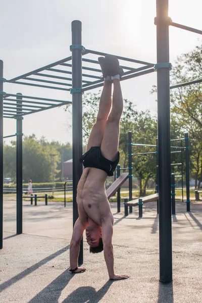 Hombre musculoso en forma joven haciendo handstand Entrenamiento al aire libre —  Fotos de Stock