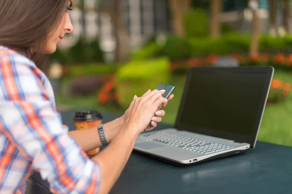 Attraktiv ung kvinna läsa ett textmeddelande på hennes mobiltelefon. Flickan sitter utomhus och använda smartphone — Stockfoto