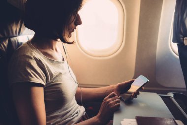 Elinde akıllı telefon olan uçakta genç kadın