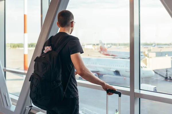 Młody człowiek stojący w pobliżu okna na lotnisku — Zdjęcie stockowe