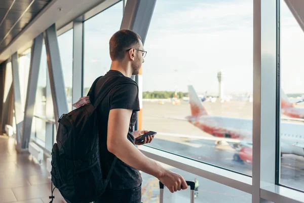 Hombre en el aeropuerto cerca de las ventanas de la puerta en los aviones en la pista . — Foto de Stock