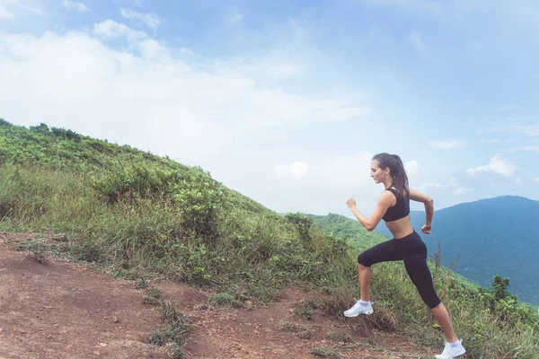 Slender joven atleta haciendo ejercicio cardiovascular subiendo la montaña con el mar en el fondo . —  Fotos de Stock