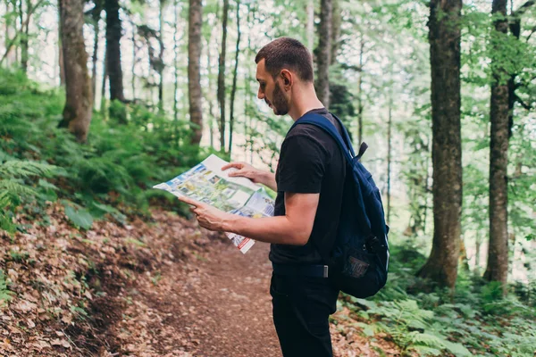Homme regardant la carte pendant la randonnée en forêt . — Photo