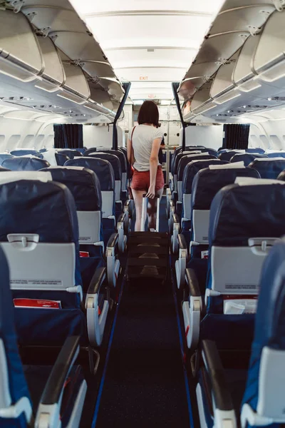 Rückansicht einer jungen Frau, die im Flugzeug durch den Gang geht — Stockfoto