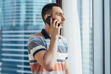 Office penceresinde tarafından Smartphone ayakta tutan işadamı