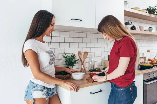 Två flickor vänner förbereder middag i köket matlagning sallad. — Stockfoto