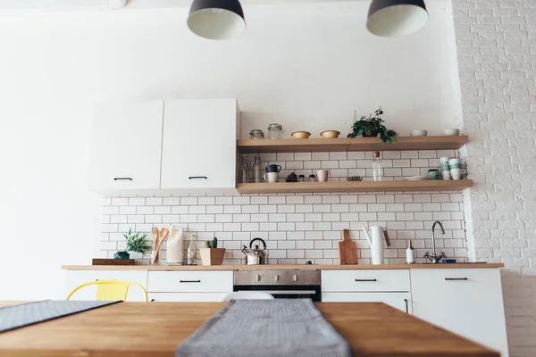 Moderno interior de luz nueva de cocina con muebles blancos y mesa de comedor. — Foto de Stock