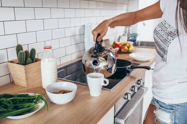 Frau gießt kochendes Wasser aus Wasserkocher in eine Tasse. — Stockfoto