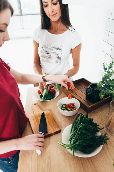 Två flickor vänner förbereder middag i köket matlagning sallad. — Stockfoto