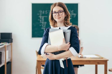 Liseli kız sınıfta kitaplarla gülümseyen portresi