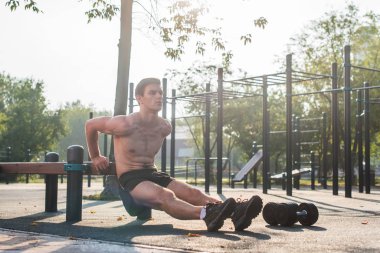 Genç adam triceps dips açık çapraz eğitim egzersiz sırasında yapıyor yerleştirmek. Fitness erkek modeli.