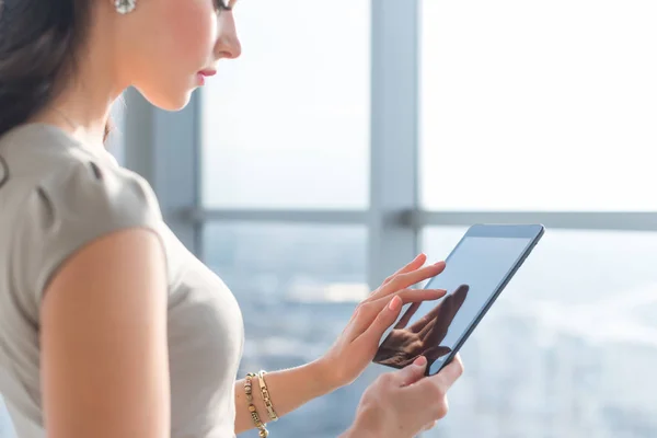 Foto de vista lateral de una joven teletrabajadora usando tableta, buscando y buscando información a través de la aplicación de conexión wi-fi en la oficina o en casa . —  Fotos de Stock