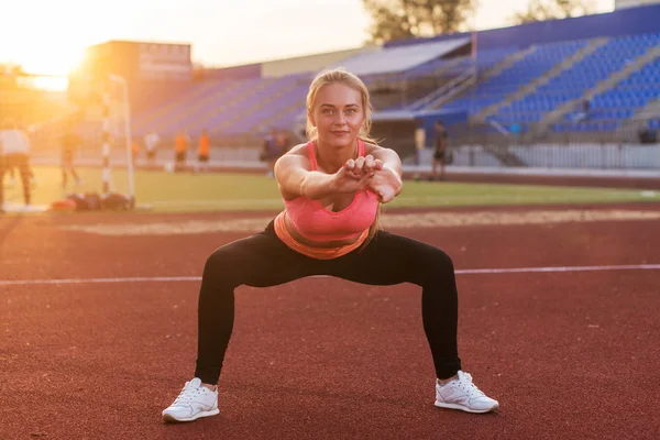 Mulher fitness fazendo agachamento exercício no estádio. Treinamento ao ar livre — Fotografia de Stock