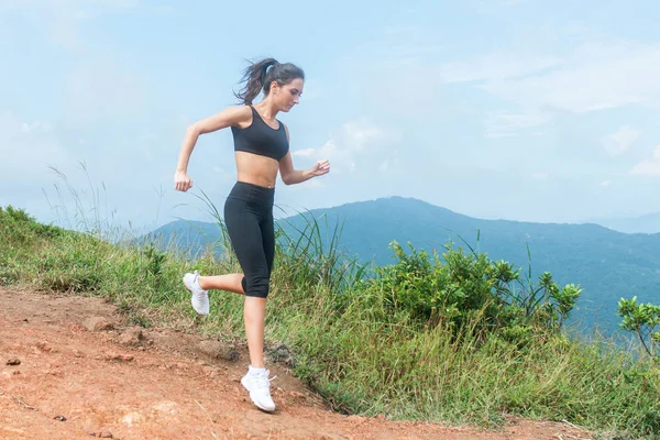 Yaz aylarında dağ yolu üzerinde çalışan arazi kadın runner iz. Vahşi doğada açık havada egzersiz siyah spor giyim giyen kadın — Stok fotoğraf