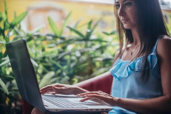 Ung kvinna som arbetar med laptop sitter på café — Stockfoto