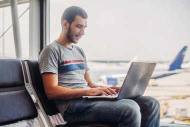 Havaalanı terminal dizüstü bilgisayar kullanan genç adam